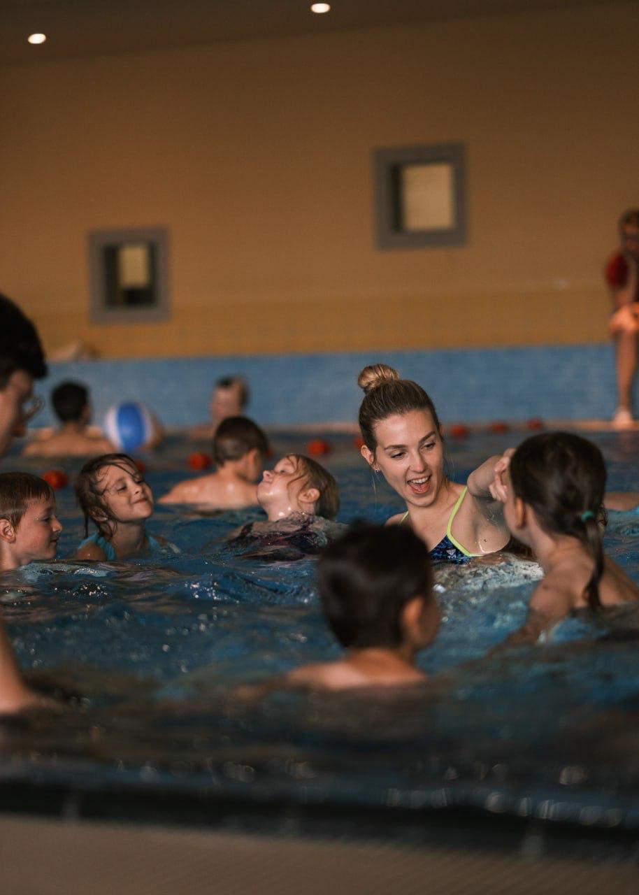 Schwimmtrainerin übt gemeinsam mit einer Kindergruppe im Wasser